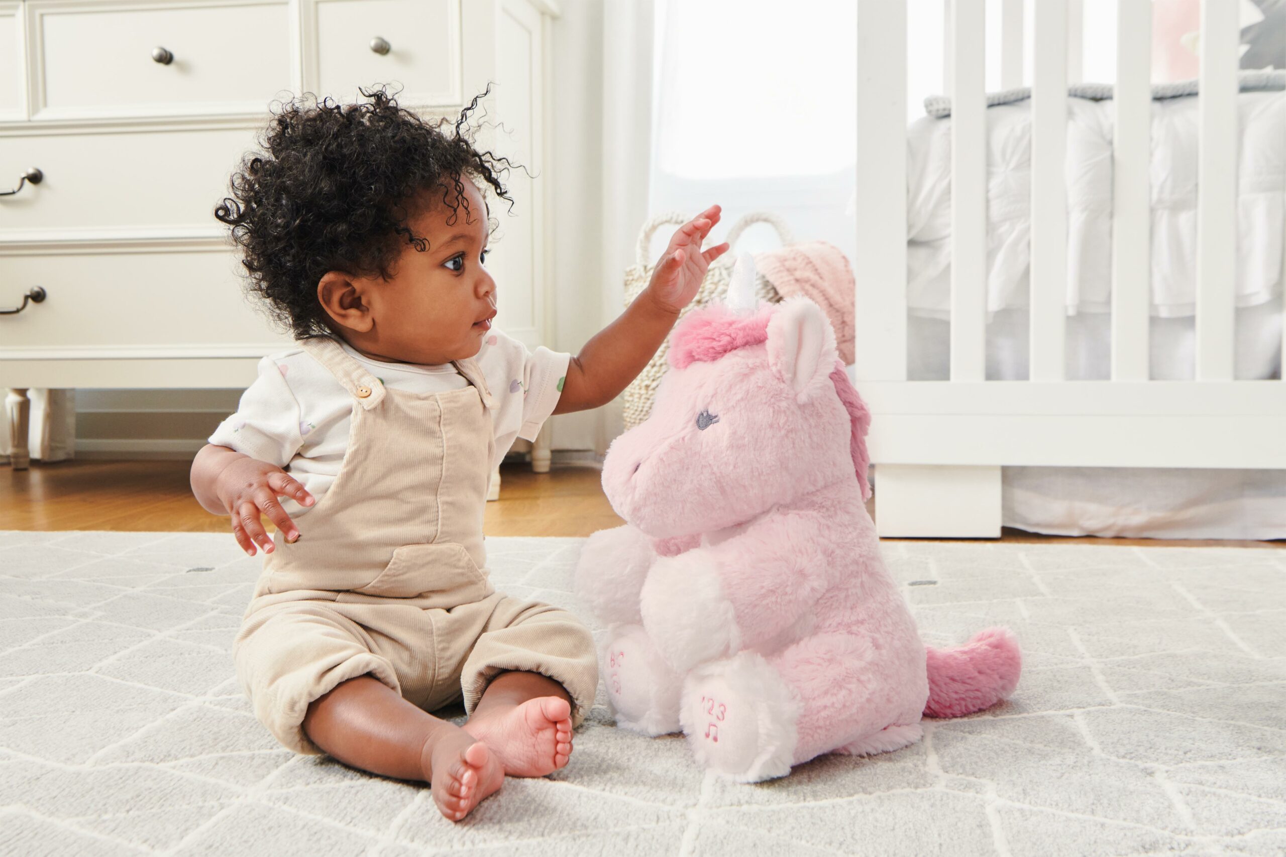 Baby playing with a GUND unicorn plush toy