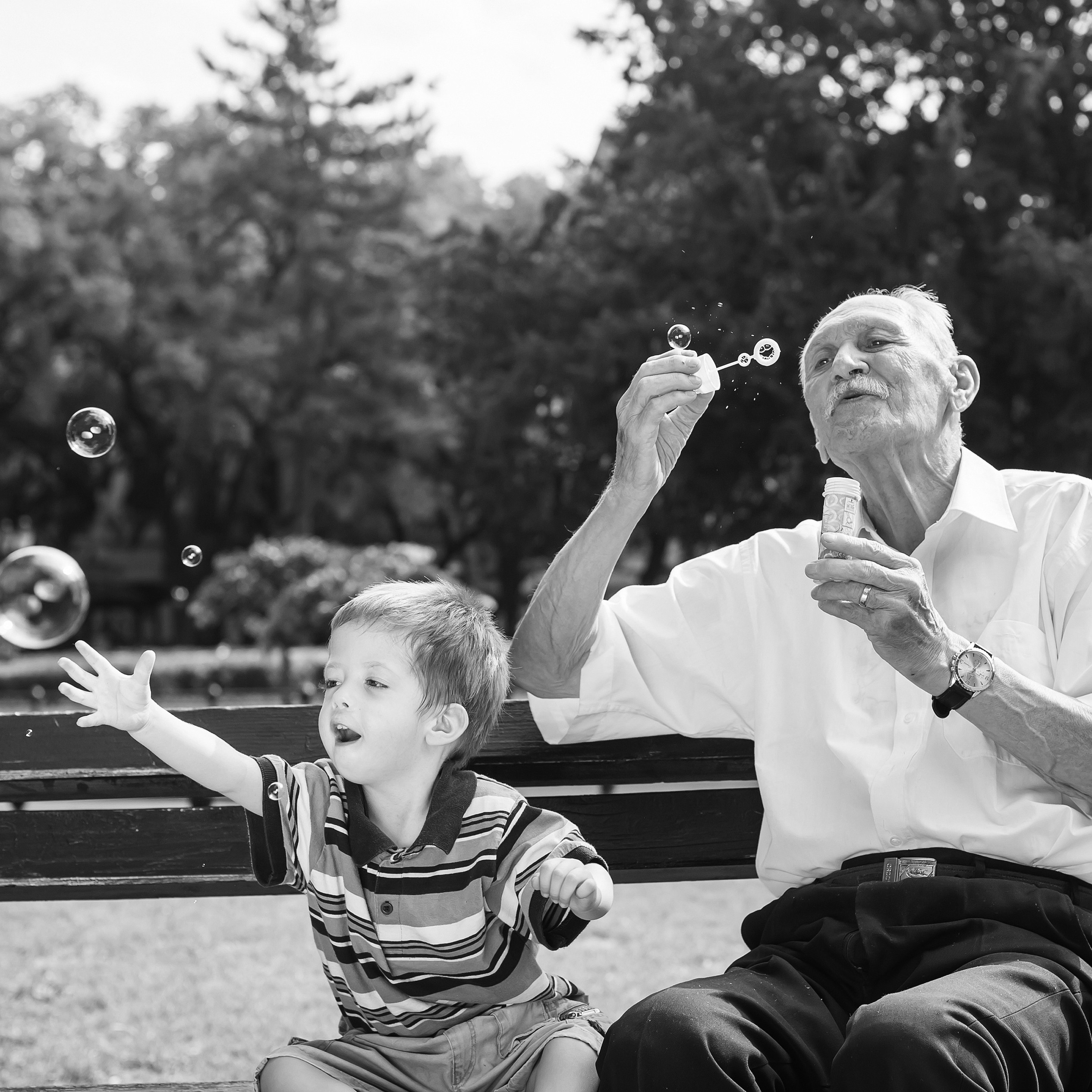 Grandfather and boy blowing bubbles