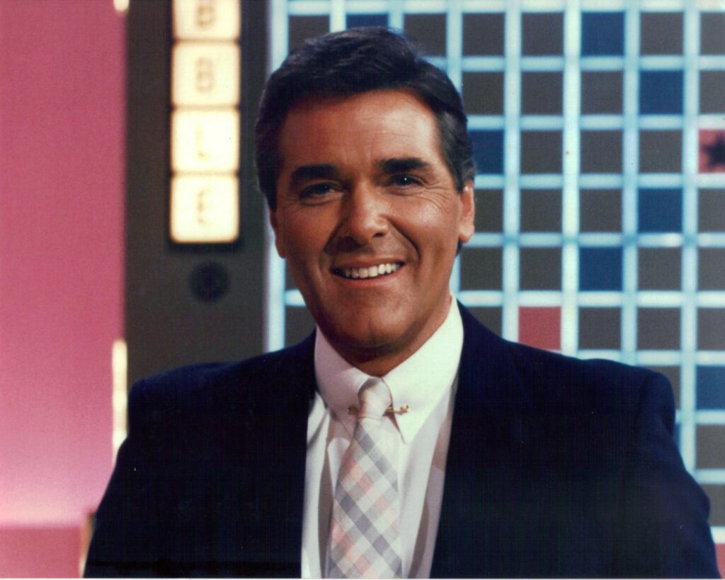 Headshot of Chuck Woolery on the set of Scrabble; has an engaging smile