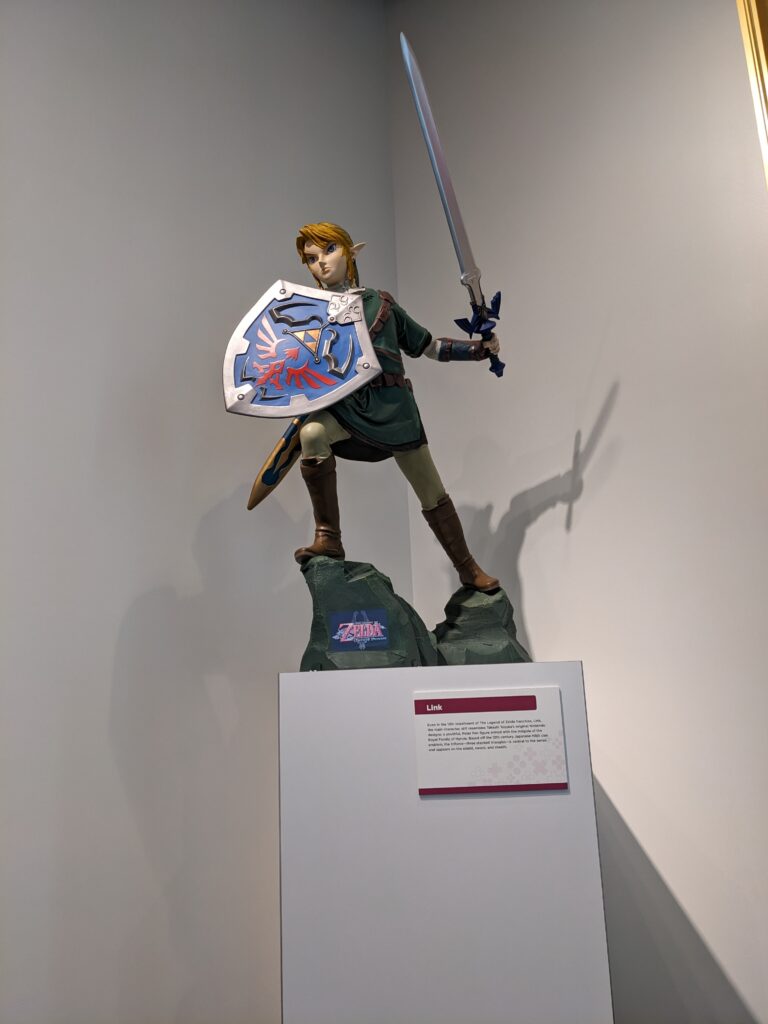 Picture of Link statue from The Legend of Zelda peers down on passers-by displayed with his sword and shield.