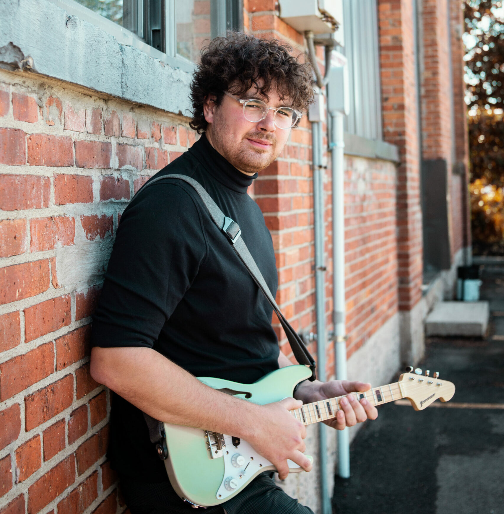 Musician Sam Nitsch holding a blue guitar.